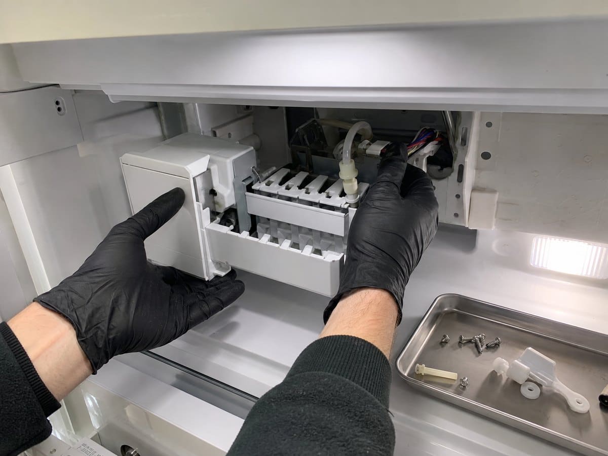 Technician checking a Sub-Zero ice-maker fill line and water connection during a Montclair leak diagnosis