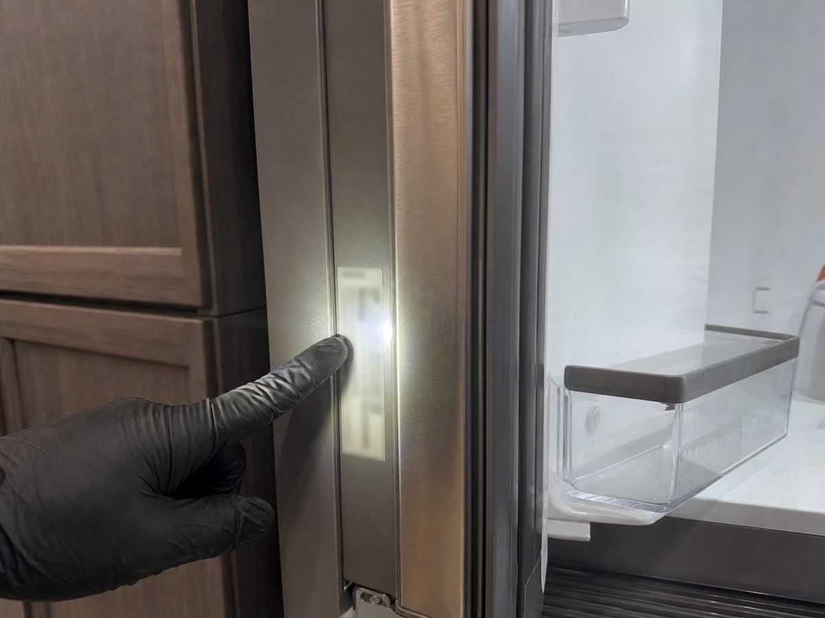Close-up of a built-in refrigerator model and serial tag inside the cabinet