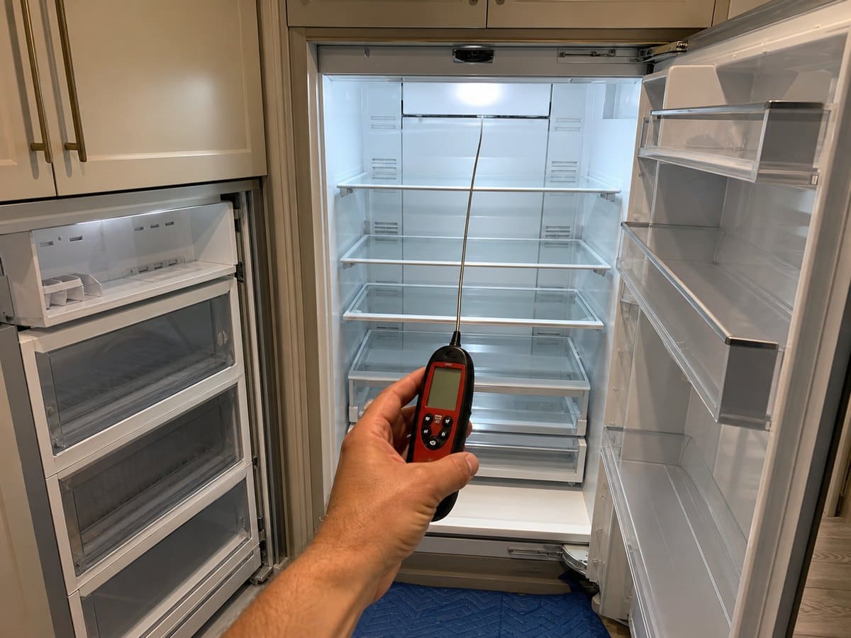 Digital probe thermometer verifying refrigerator temperature after service