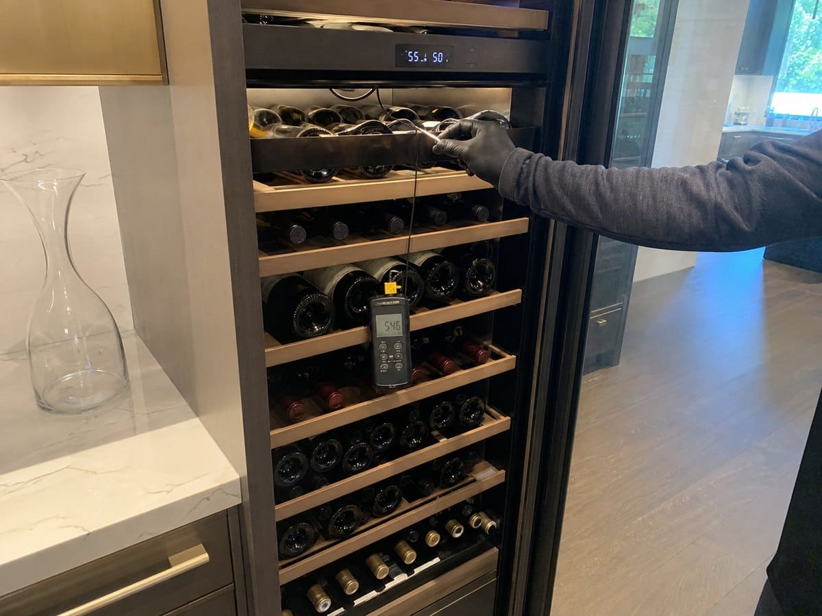 Technician checking a dual-zone wine column with a temperature probe